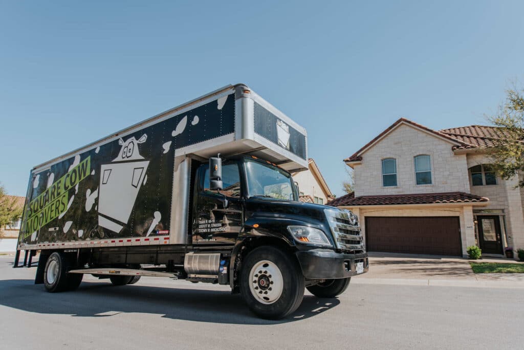 Square Cow Movers truck parked on a residential street in front of a house