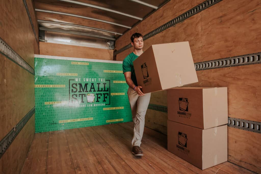 Mover carrying a cardboard box inside a moving truck