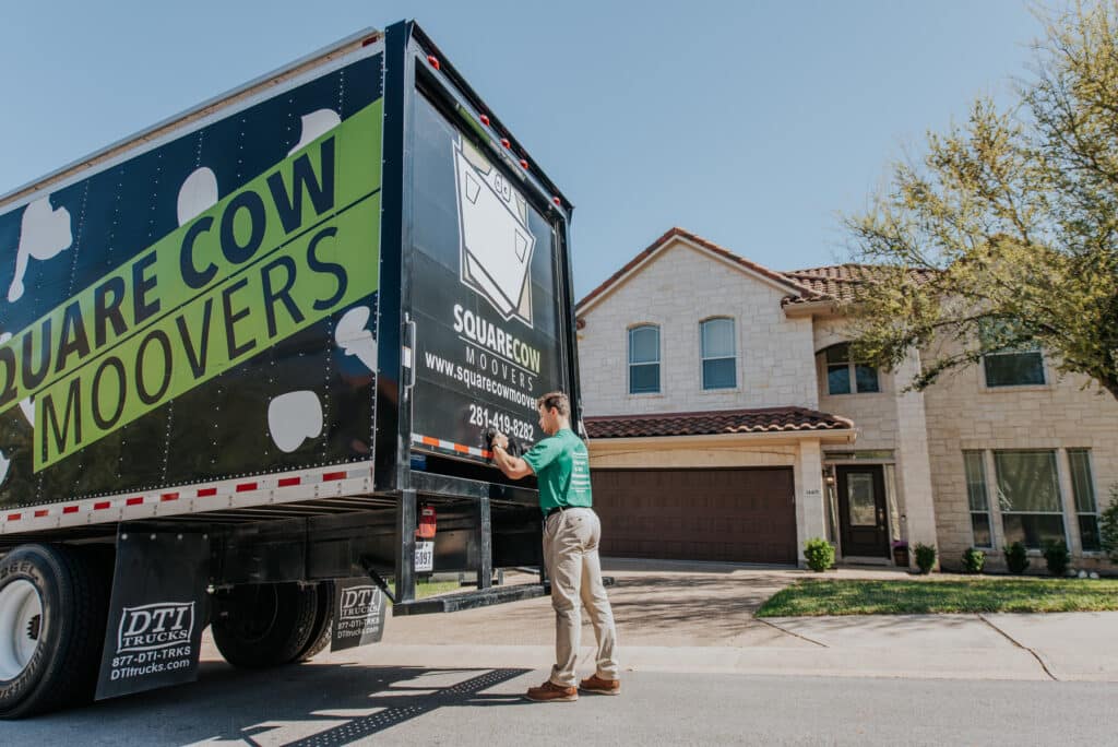 Moving truck parked in front of a house with a mover at the back door