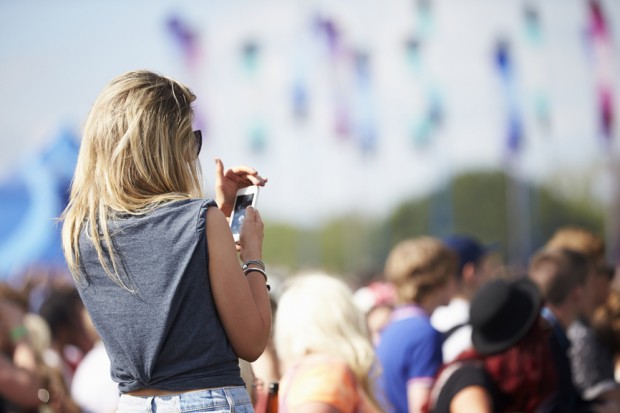 Young Woman At Outdoor Music Festival Using Mobile Phone