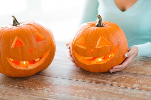 holidays, halloween, decoration and people concept - close up of woman with pumpkins at home