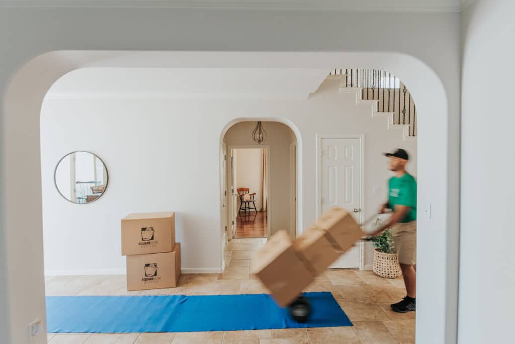 A man is carrying boxes into a house, preparing for a move