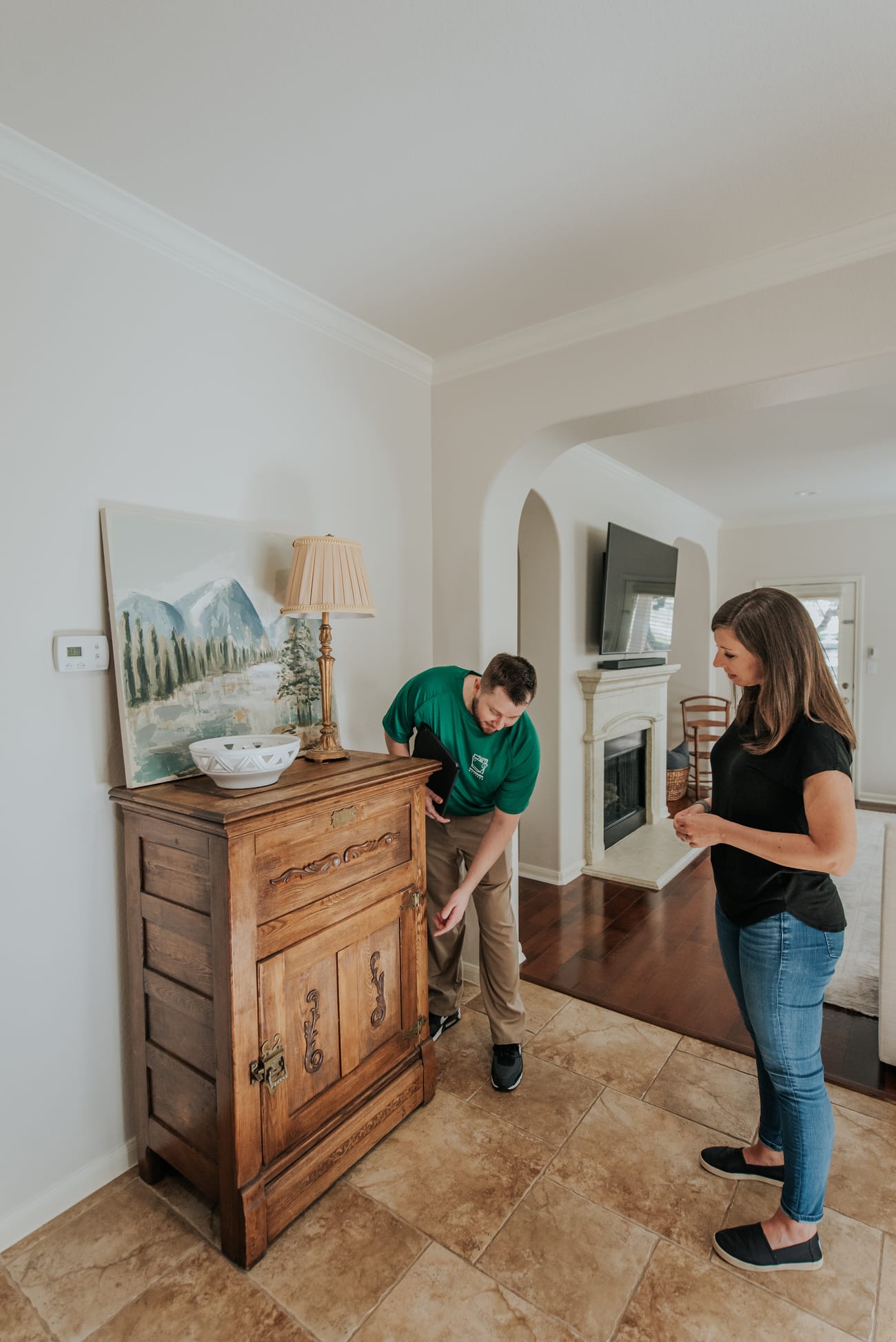 A man and woman stand together in a cozy living room, surrounded by furniture and decor
