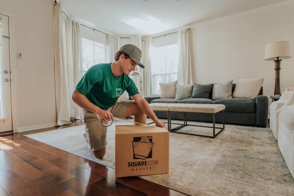 A man in a green shirt is lifting and moving a box in a well-lit indoor space