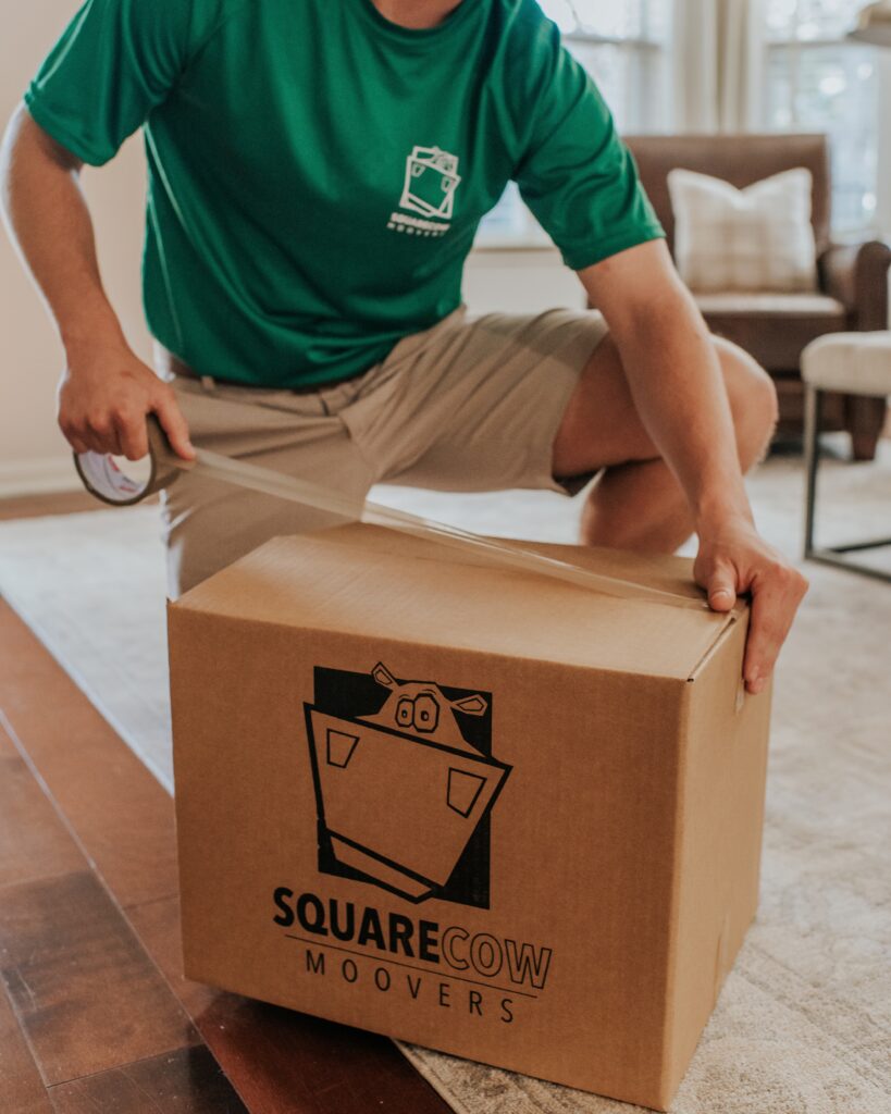 A worker seals a box with tape, preparing it for moving.