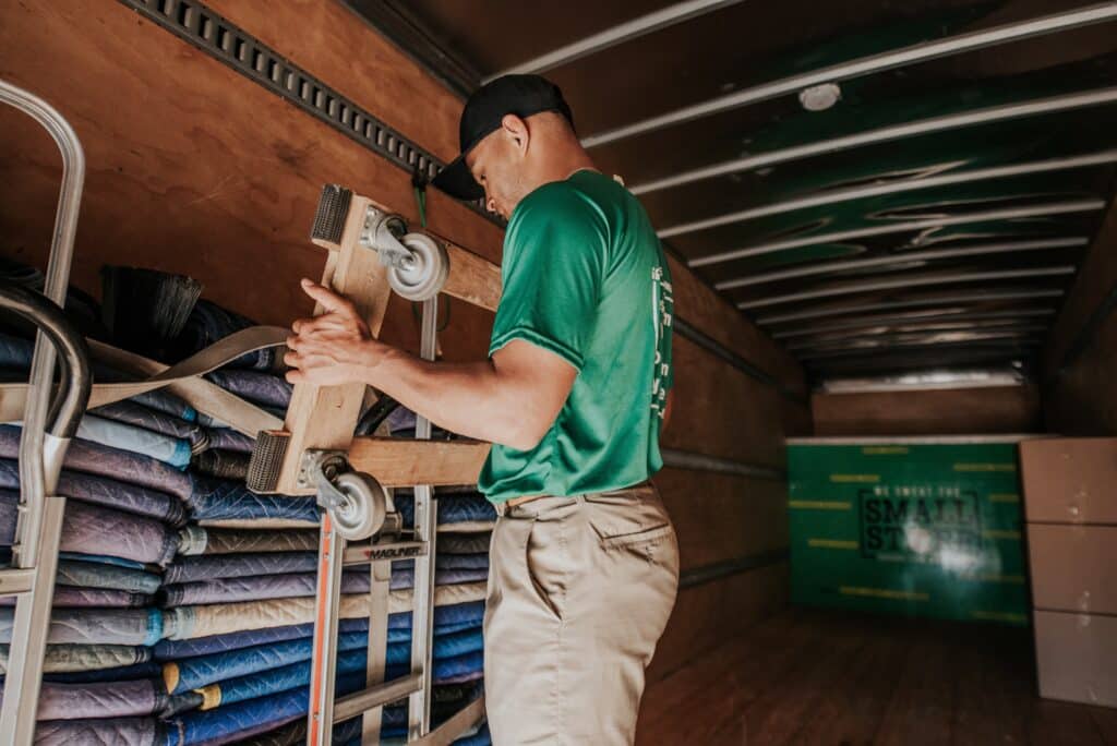 Mover adjusting a dolly with wheels inside a truck.