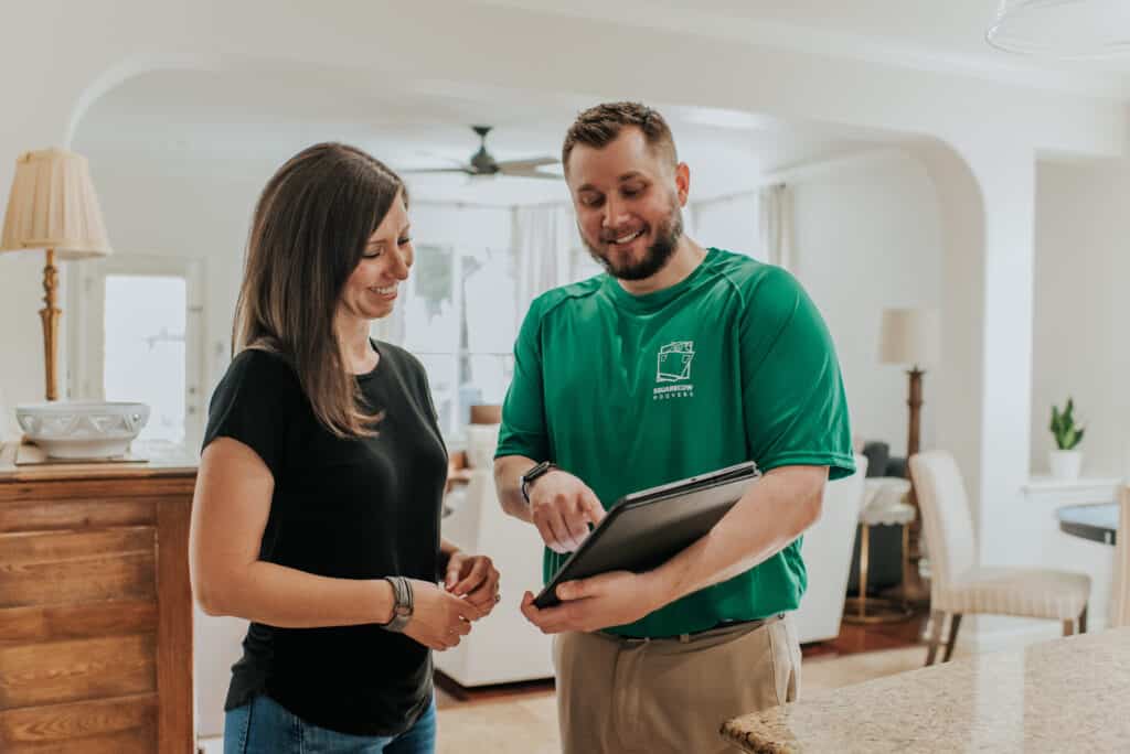 A customer and a Square Cow Movers employee discuss moving details in a home kitchen.