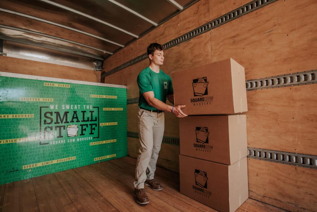 Mover stacking Square Cow Movers boxes inside a moving truck
