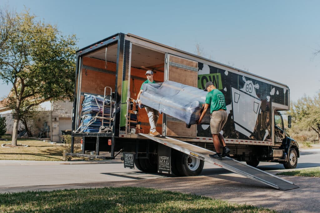 Movers loading wrapped furniture into a Square Cow Movers truck
