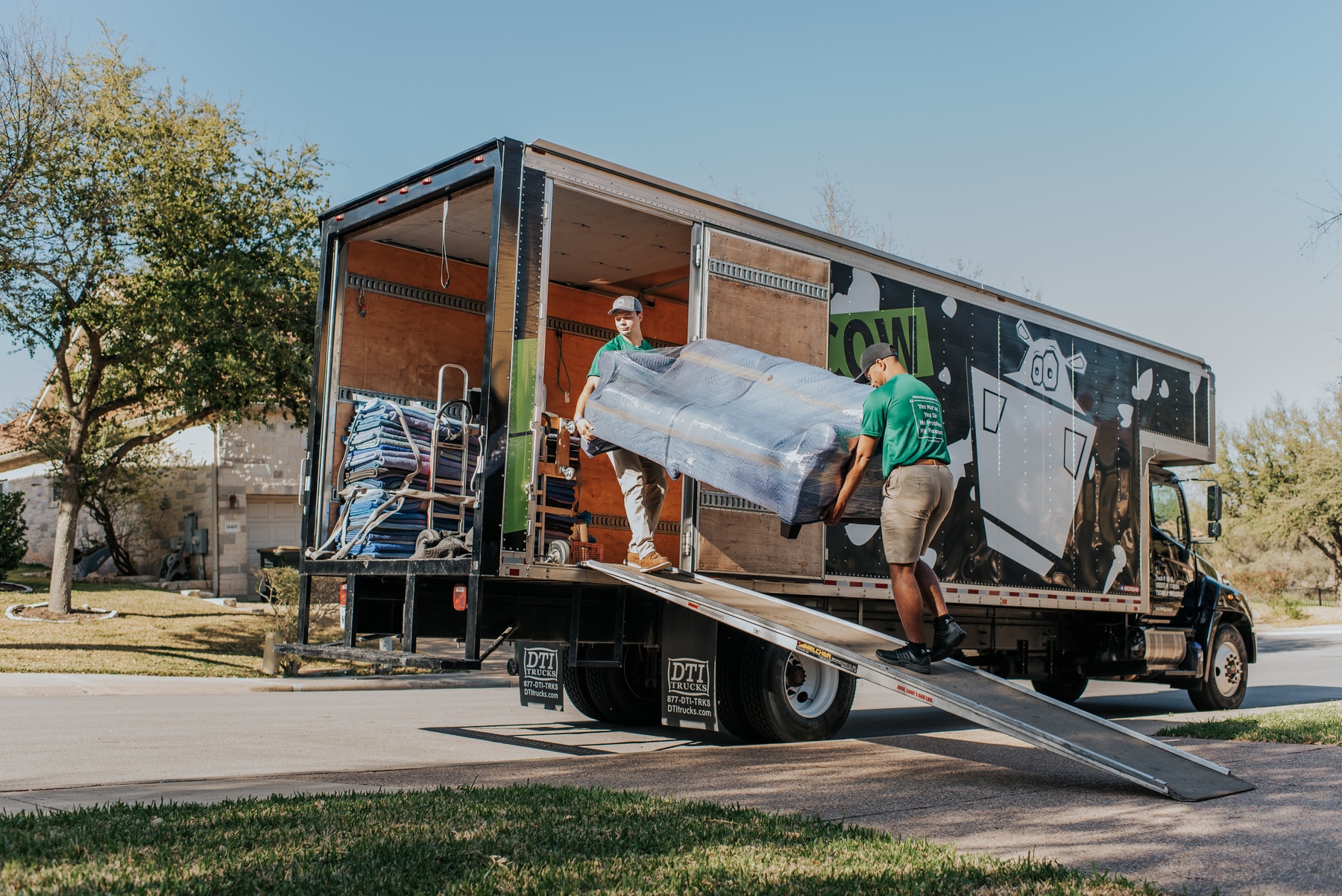 Movers loading wrapped furniture into a Square Cow Movers truck