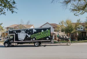 Square Cow Movers team carrying a couch into a moving truck