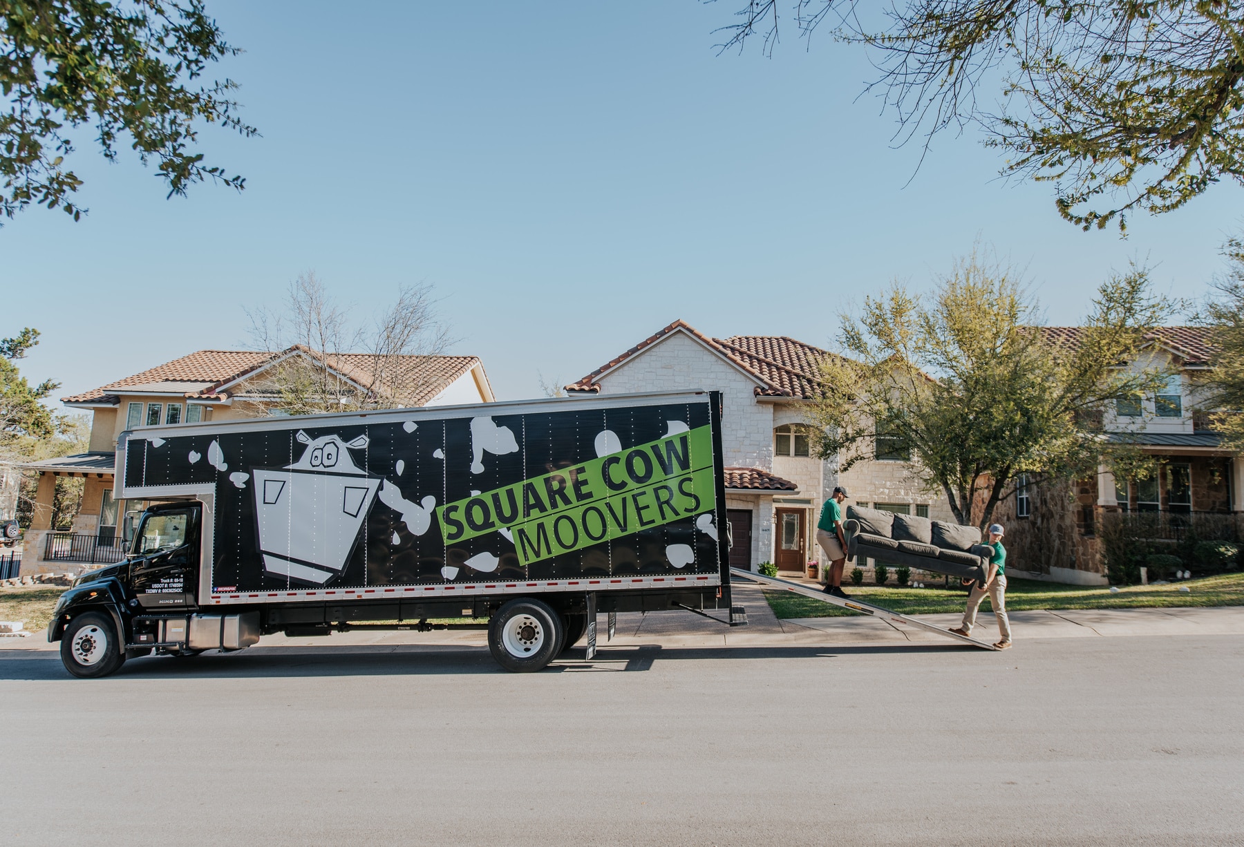 Square Cow Movers team carrying a couch into a moving truck