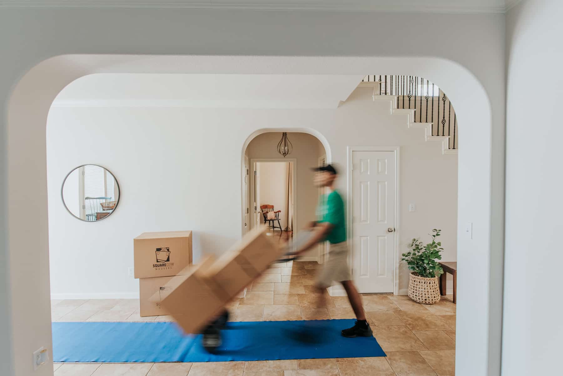 Square Cow Movers employee carrying boxes through a home