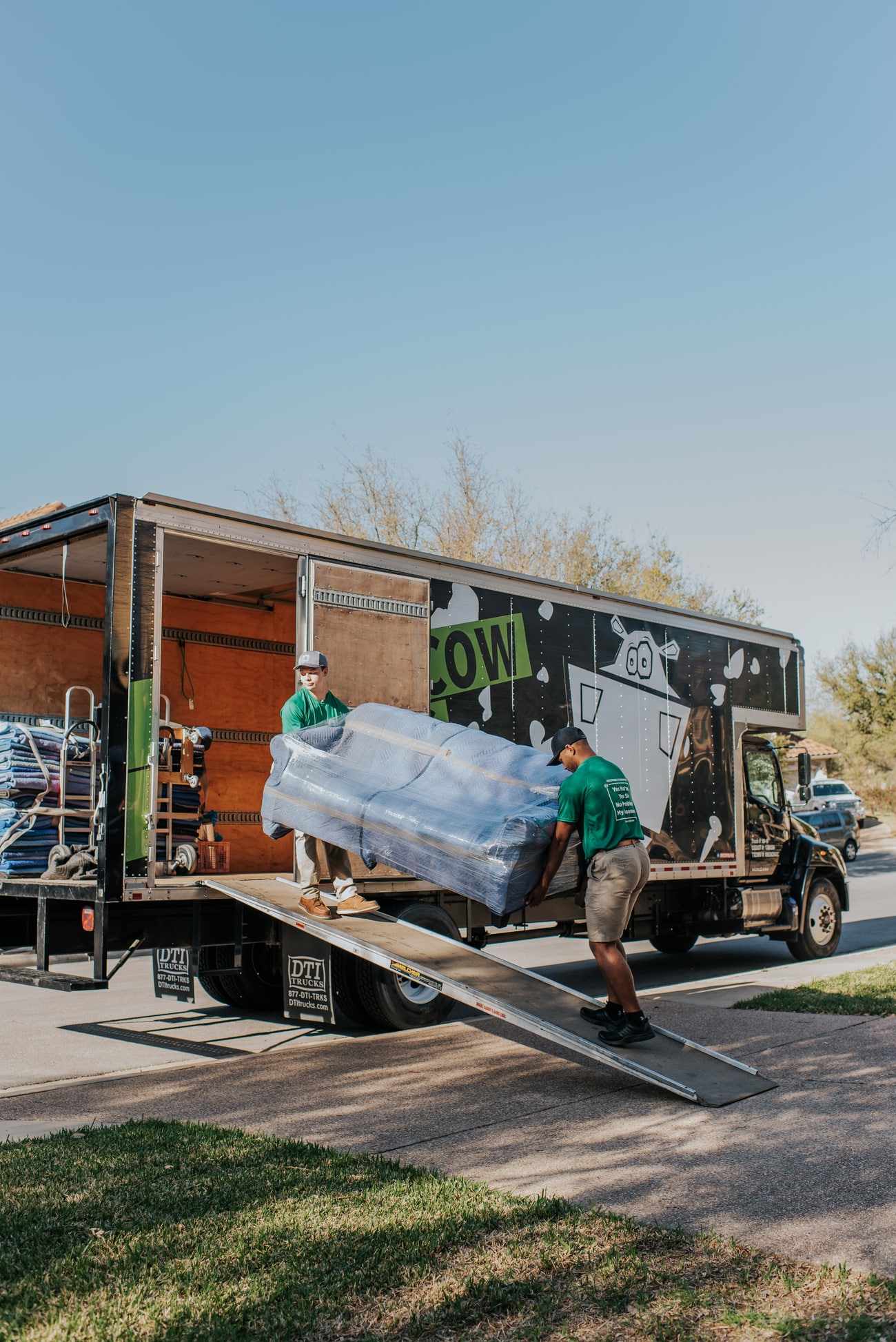 Square Cow Movers team loading a wrapped sofa onto a truck