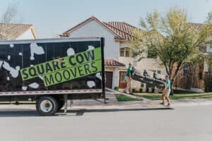 Square Cow Movers team loading a sofa onto a moving truck