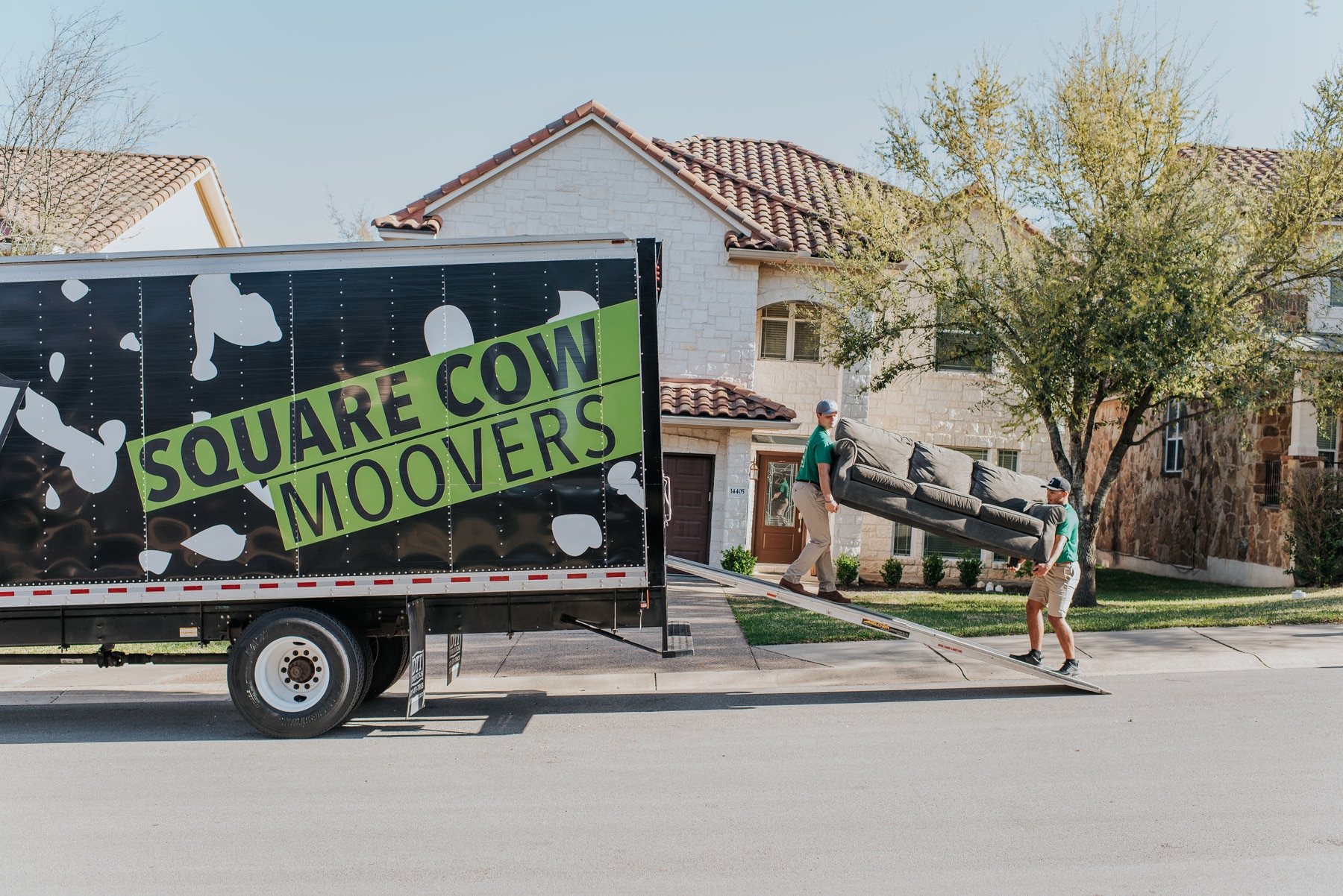 Square Cow Movers team loading a sofa onto a moving truck