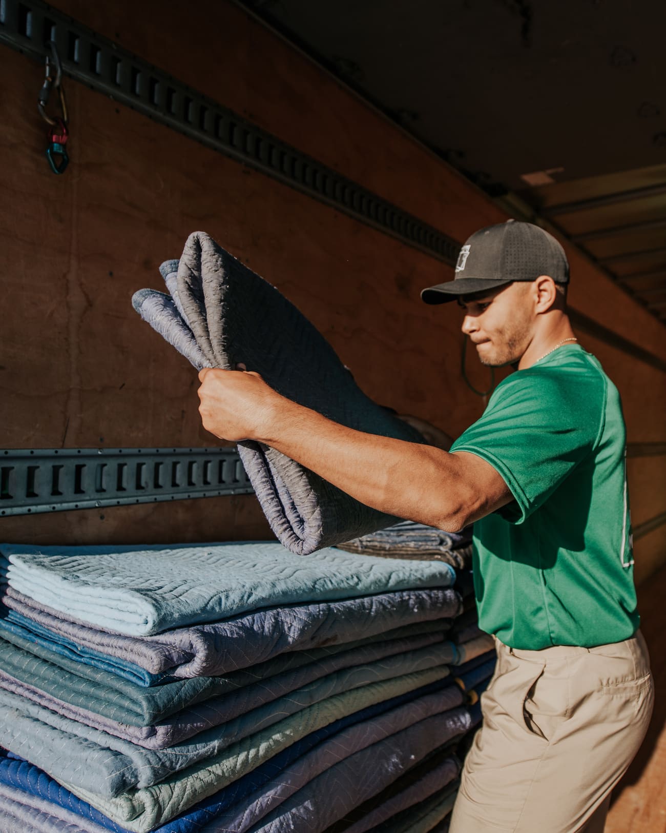 Square Cow Movers mover organizing moving blankets inside a moving truck