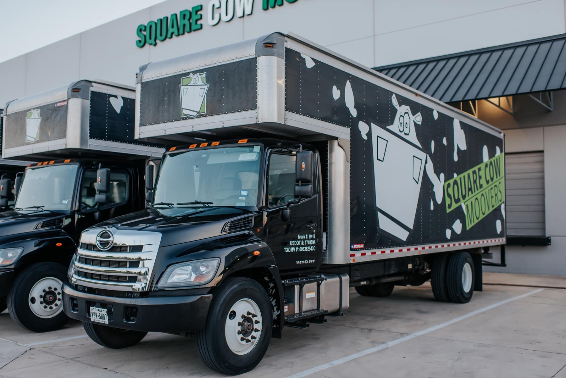 Square Cow Movers moving trucks parked outside the company warehouse